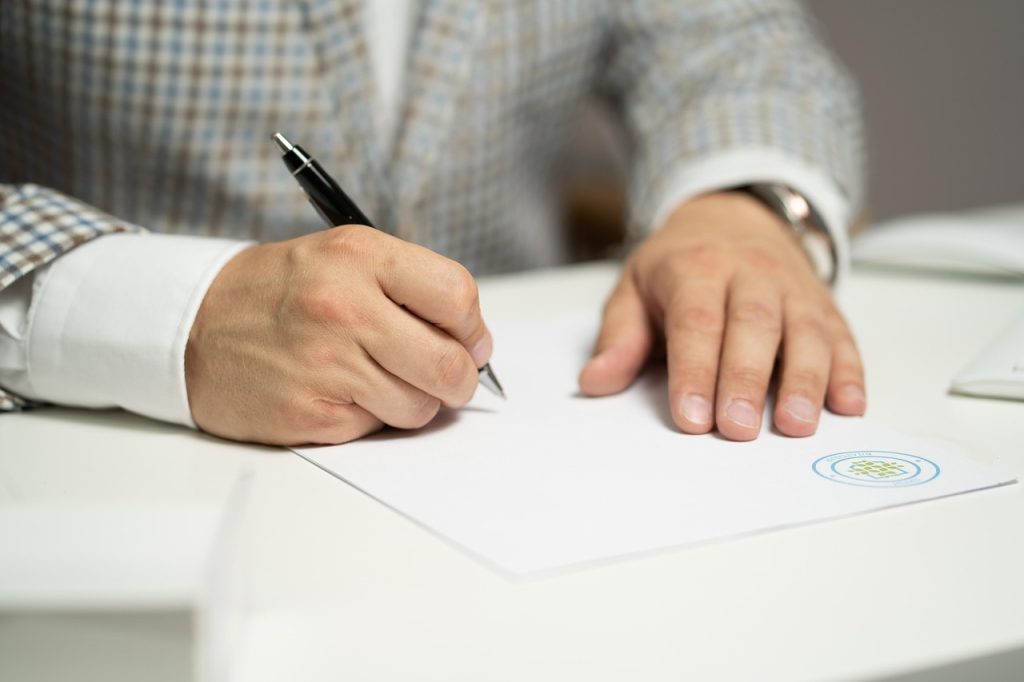 Crédito pessoal fica mais barato em outubro, mas taxa ainda pesa no bolso, diz Procon-SP Pessoa assinando um contrato sobre uma mesa.